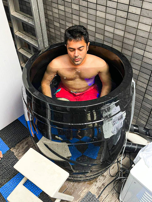 A man inmersed in a cold plunge ice barrel